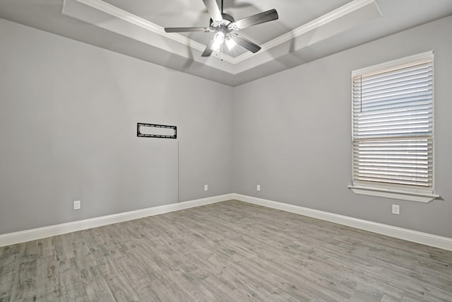 unfurnished room featuring a raised ceiling, wood-type flooring, ornamental molding, and ceiling fan