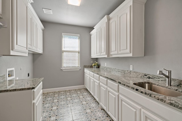 kitchen with white cabinetry, sink, light tile patterned floors, and light stone counters