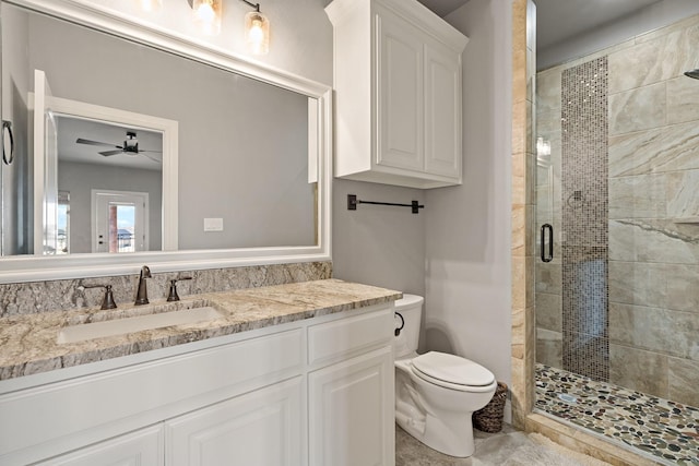 bathroom with vanity, ceiling fan, a shower with shower door, and toilet