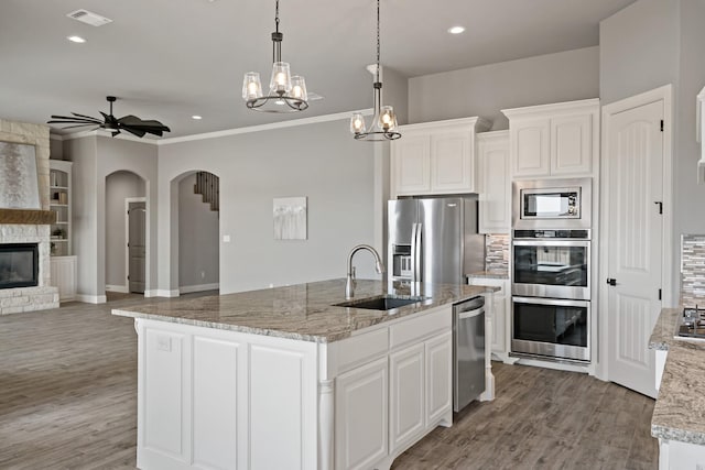 kitchen with a fireplace, white cabinetry, sink, a kitchen island with sink, and stainless steel appliances