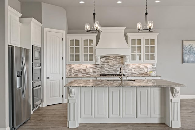 kitchen featuring a kitchen island with sink, hanging light fixtures, white cabinets, and appliances with stainless steel finishes