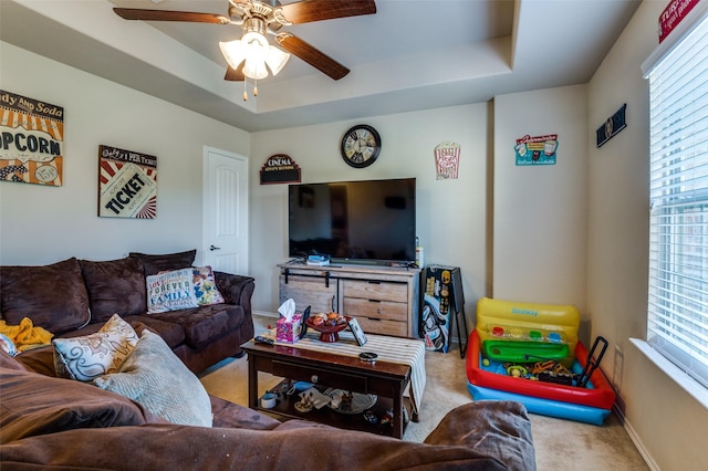 carpeted living room with ceiling fan and a raised ceiling