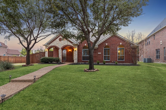 ranch-style home featuring a yard and central air condition unit