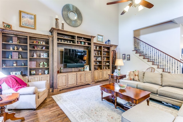 living room with a towering ceiling, dark wood-type flooring, and ceiling fan