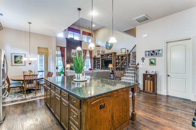 kitchen featuring a kitchen island, dark wood-type flooring, dark stone counters, and pendant lighting