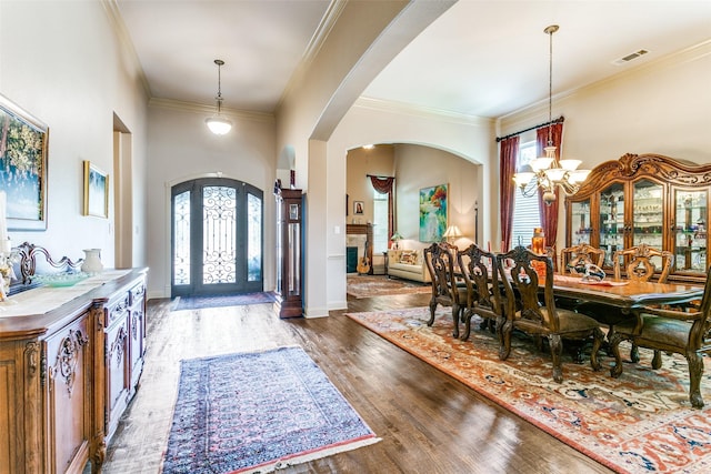 entryway featuring a towering ceiling, dark hardwood / wood-style floors, crown molding, and a chandelier