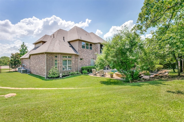 rear view of property featuring a patio, central air condition unit, and a yard