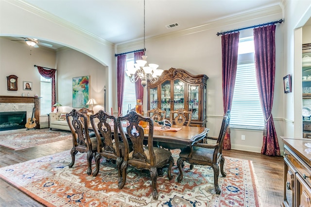 dining area with ornamental molding, ceiling fan with notable chandelier, and wood-type flooring