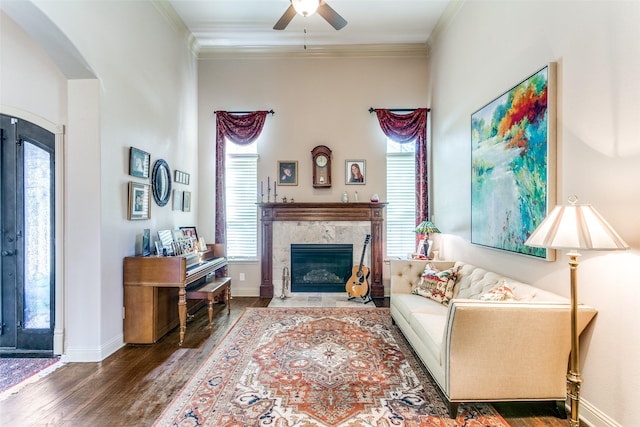 living room featuring dark hardwood / wood-style flooring, a fireplace, ceiling fan, and crown molding