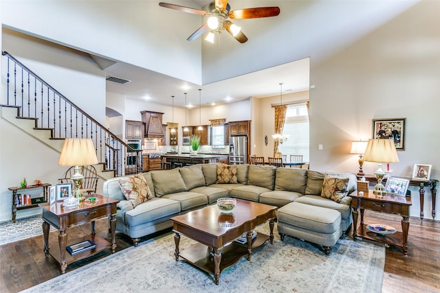 living room featuring a high ceiling, ceiling fan, and dark hardwood / wood-style flooring