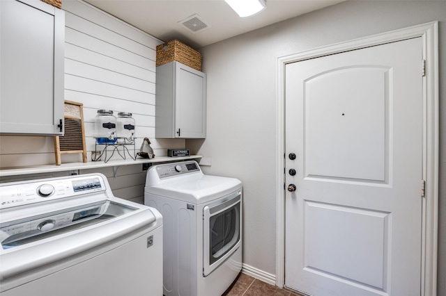 clothes washing area with cabinets, dark tile patterned floors, and washer and clothes dryer