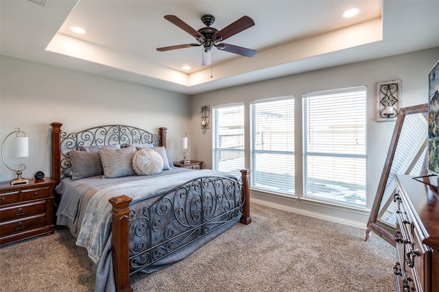 bedroom featuring a raised ceiling, ceiling fan, and carpet