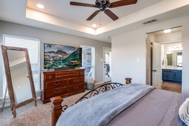 bedroom featuring a raised ceiling, ceiling fan, and multiple windows