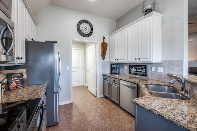 kitchen with sink, stainless steel appliances, white cabinetry, light tile patterned flooring, and dark stone counters