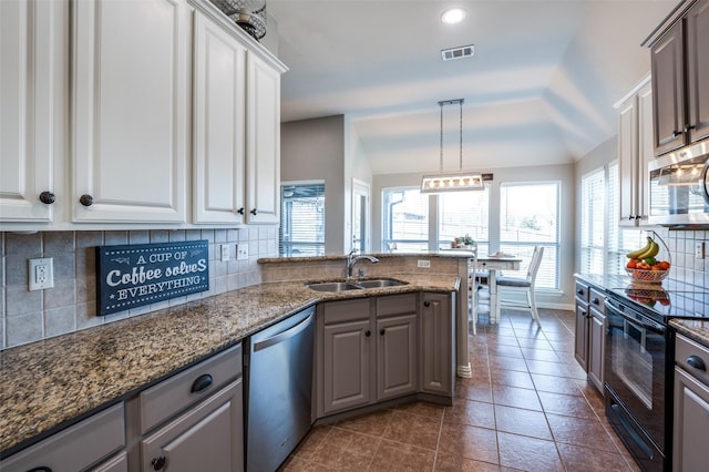 kitchen featuring vaulted ceiling, appliances with stainless steel finishes, hanging light fixtures, white cabinets, and sink