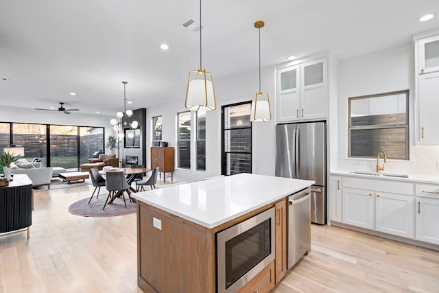 kitchen featuring white cabinets, decorative light fixtures, appliances with stainless steel finishes, and sink