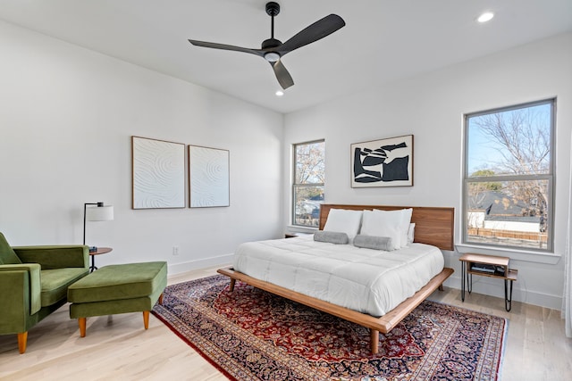 bedroom with ceiling fan, light hardwood / wood-style flooring, and multiple windows