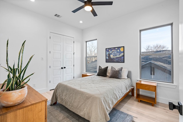 bedroom featuring ceiling fan, light hardwood / wood-style flooring, and a closet