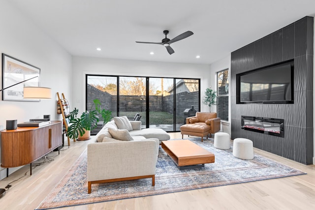 living room featuring a fireplace, ceiling fan, and light hardwood / wood-style floors