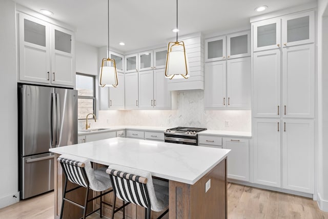 kitchen with stainless steel appliances, a kitchen island, white cabinetry, and sink