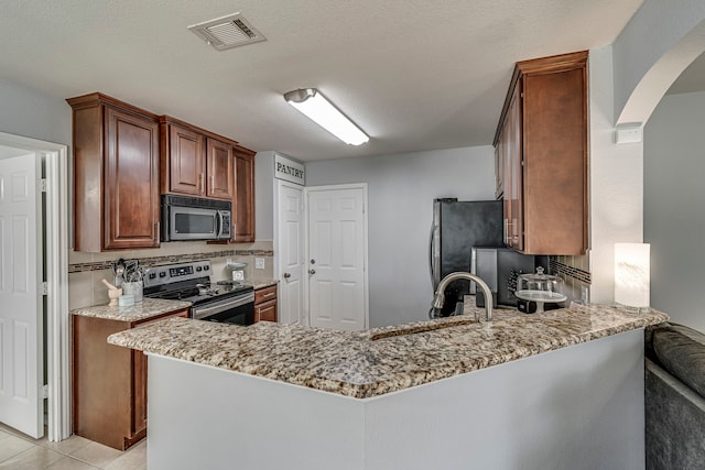 kitchen featuring light stone counters, kitchen peninsula, appliances with stainless steel finishes, and light tile patterned floors