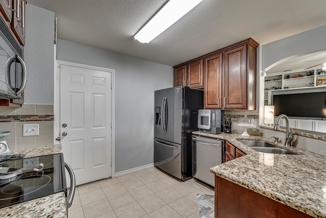 kitchen featuring appliances with stainless steel finishes, light stone countertops, ceiling fan, sink, and tasteful backsplash