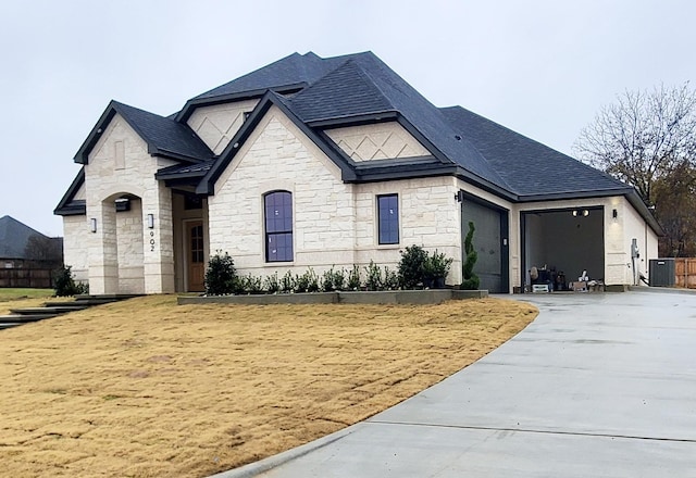 french country inspired facade featuring central AC and a garage