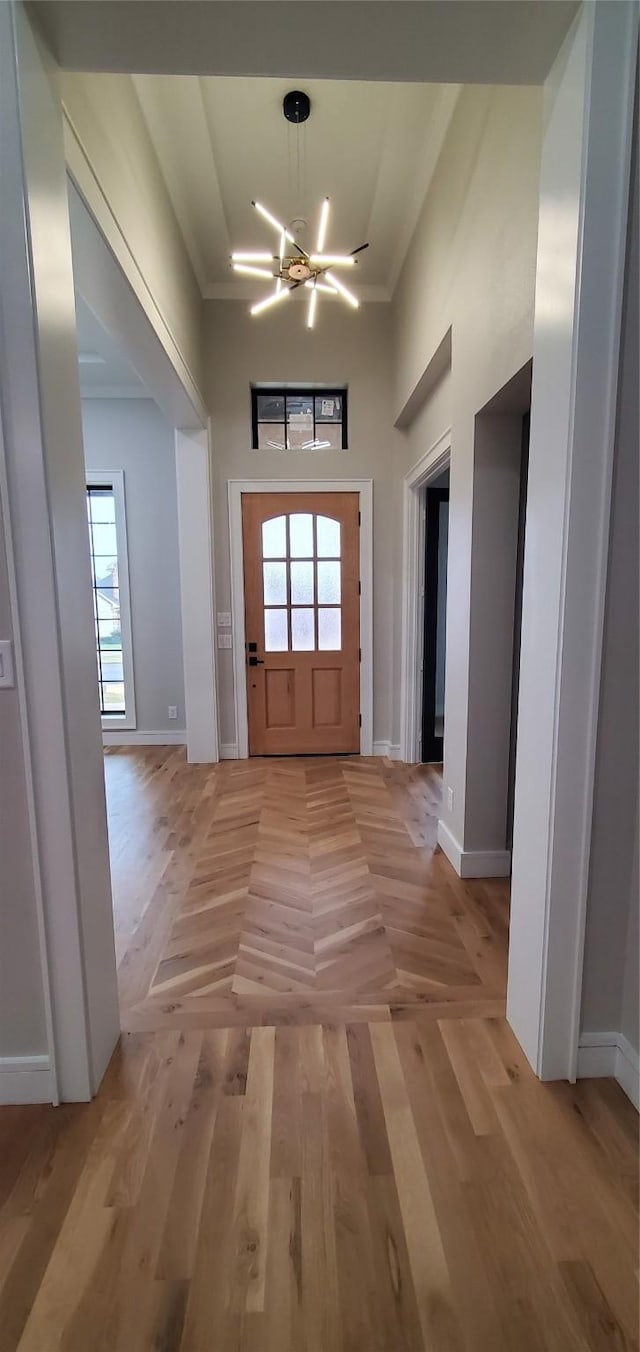 foyer entrance featuring an inviting chandelier, ornamental molding, and a wealth of natural light