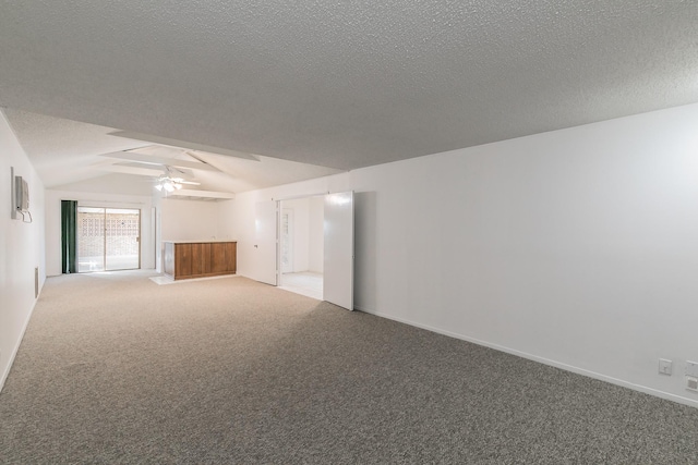 empty room with a textured ceiling, carpet, ceiling fan, and vaulted ceiling