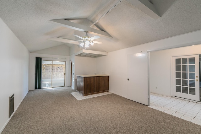 empty room with a textured ceiling, ceiling fan, light carpet, and vaulted ceiling with beams