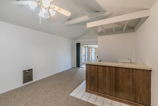 kitchen with light carpet, heating unit, vaulted ceiling with beams, kitchen peninsula, and ceiling fan