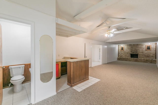 interior space featuring ceiling fan, a brick fireplace, and light tile patterned floors