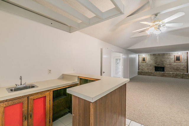 kitchen featuring sink, a fireplace, ceiling fan, brick wall, and light colored carpet