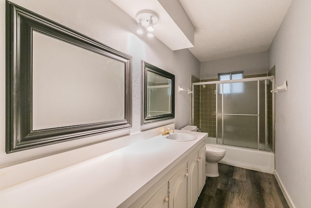 full bathroom with bath / shower combo with glass door, toilet, vanity, and hardwood / wood-style flooring