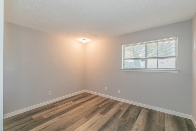 spare room with a textured ceiling and dark wood-type flooring