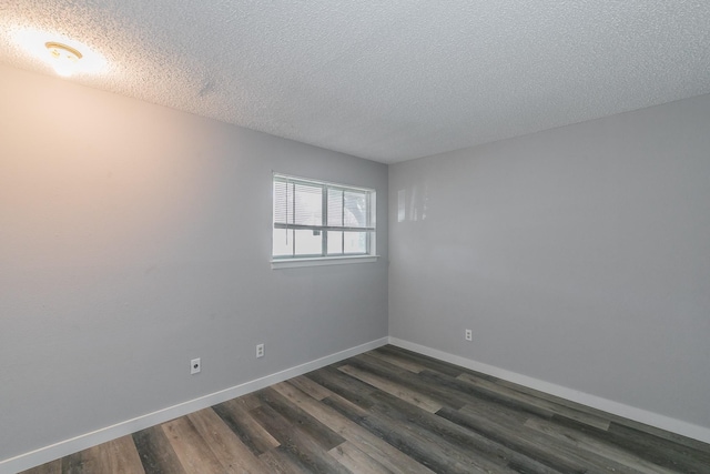 spare room featuring dark wood-type flooring and a textured ceiling