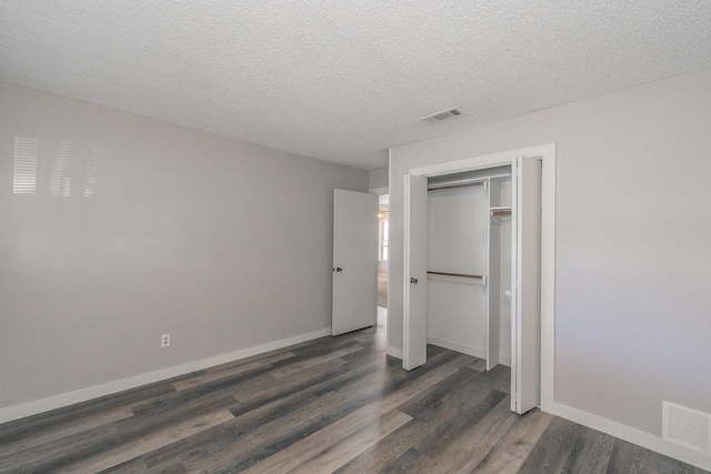 unfurnished bedroom featuring dark wood-type flooring, a textured ceiling, and a closet