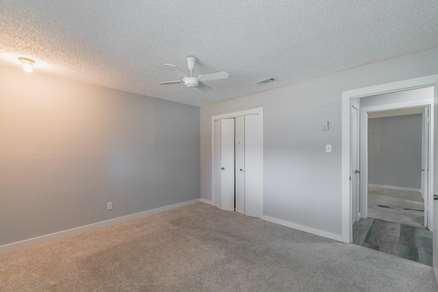 unfurnished bedroom featuring carpet flooring, a closet, ceiling fan, and a textured ceiling