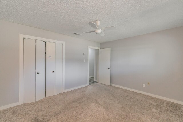 unfurnished bedroom with carpet, a closet, ceiling fan, and a textured ceiling