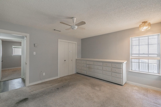 unfurnished bedroom with a closet, multiple windows, light carpet, and ceiling fan