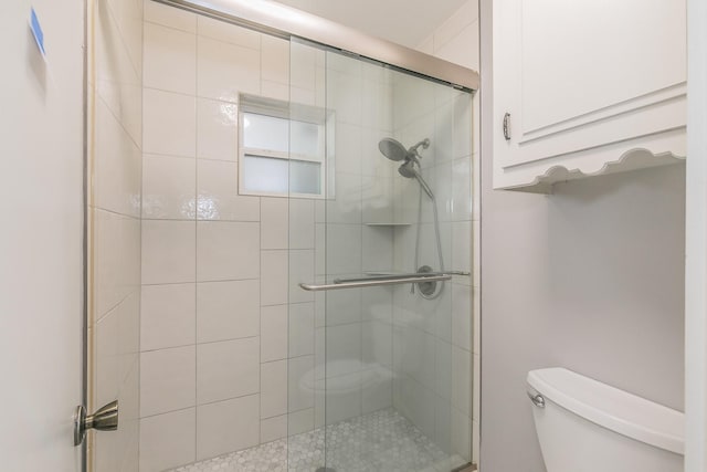 bathroom with toilet and a shower with shower door