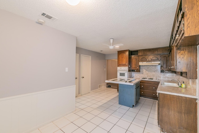 kitchen with sink, a kitchen island, white appliances, and a textured ceiling