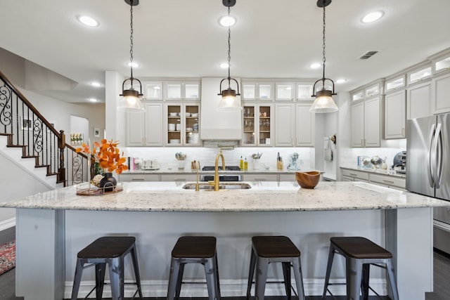 kitchen with stainless steel refrigerator, a large island, and white cabinets