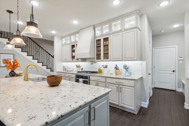 kitchen featuring sink, white cabinetry, light stone counters, custom range hood, and appliances with stainless steel finishes