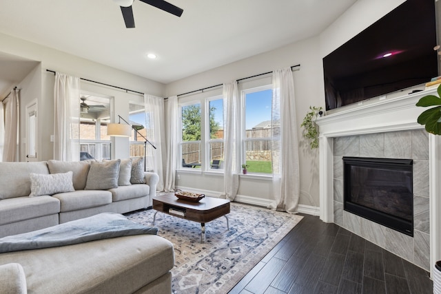 living room with a tile fireplace, ceiling fan, and wood-type flooring