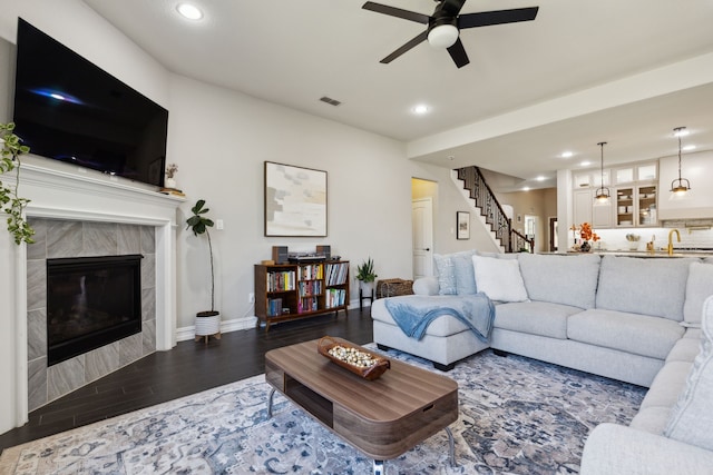 living room featuring sink, a tile fireplace, ceiling fan, and dark hardwood / wood-style floors