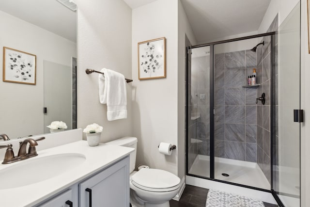 bathroom featuring toilet, vanity, a textured ceiling, and walk in shower