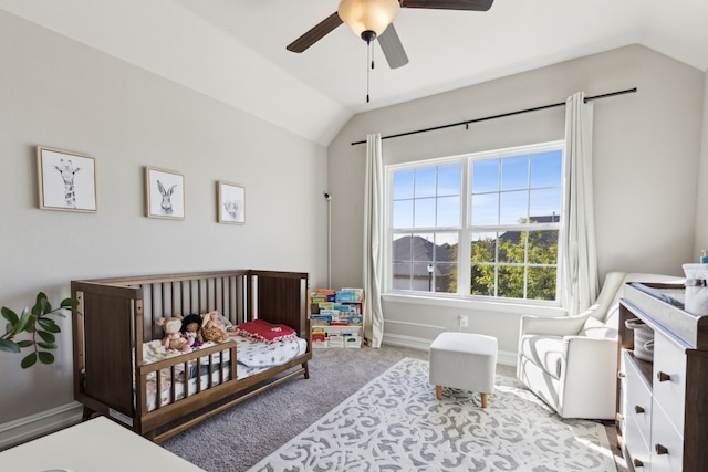 bedroom featuring ceiling fan, light carpet, vaulted ceiling, and a crib