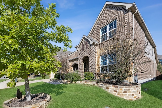 view of front facade with a front yard and brick siding