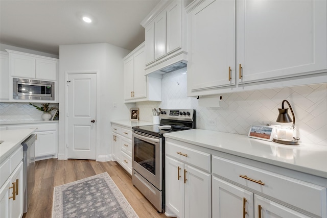 kitchen featuring decorative backsplash, white cabinetry, appliances with stainless steel finishes, and custom range hood